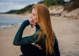 a woman sitting on a beach next to the ocean