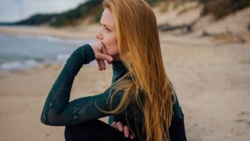 a woman sitting on a beach next to the ocean