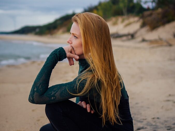 a woman sitting on a beach next to the ocean
