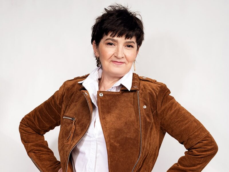 a woman in white pants and a brown jacket