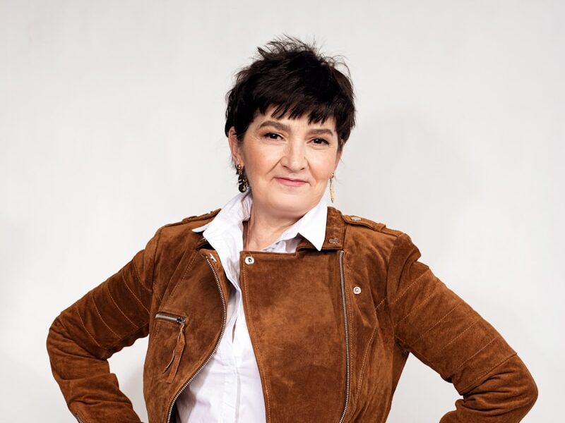 a woman in white pants and a brown jacket