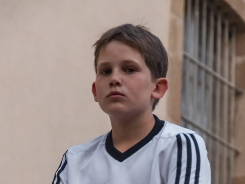 a young boy sitting on a ledge with his legs crossed