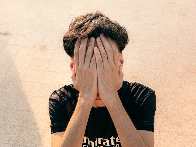 A young boy covers his face with his hands