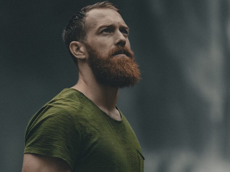 man wearing green crew-neck t-shirt looking upwards