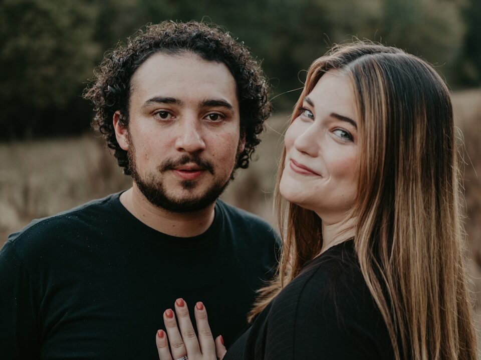 a man and woman standing next to each other in a field