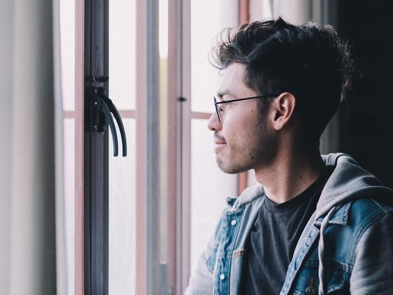 man in blue denim jacket wearing black framed eyeglasses