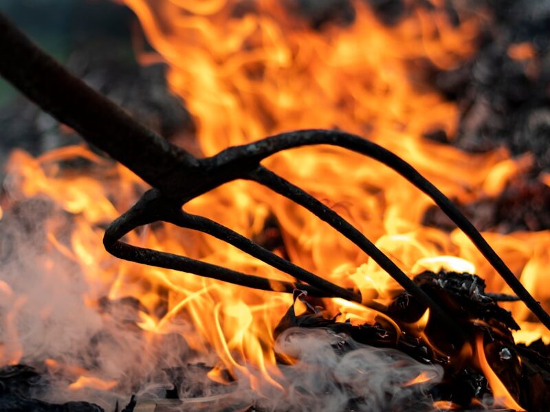 garden fork near burning wood during daytime