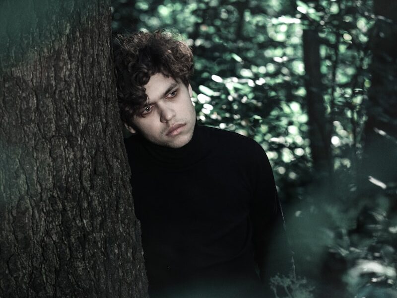 a man standing next to a tree in a forest