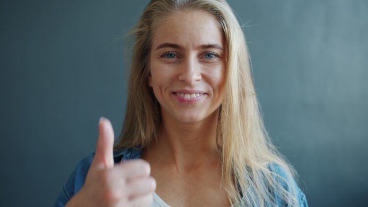 Young woman smiling and giving a thumbs up.