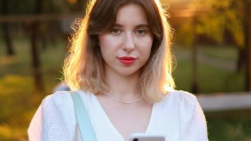a woman in a white dress holding a cell phone