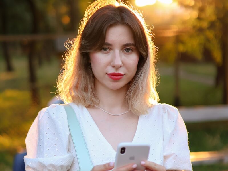 a woman in a white dress holding a cell phone