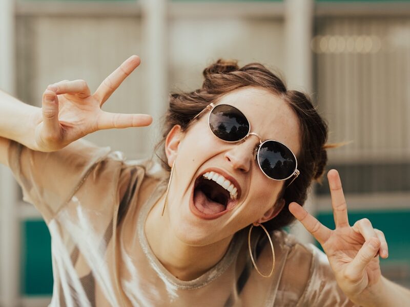 selective focus photography of jolly woman using peace hand gesture