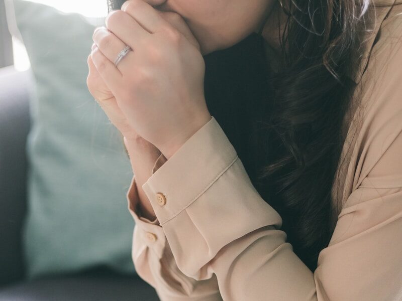 woman in beige blazer sitting on white bed