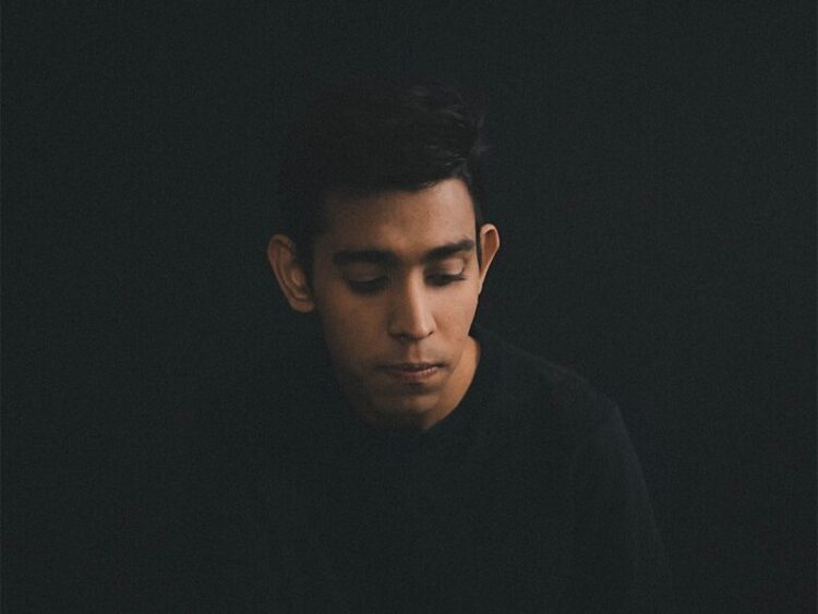 man wearing black long-sleeved shirt sitting while looking down