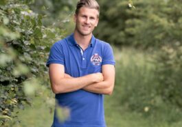 a man in a blue shirt is standing in the woods