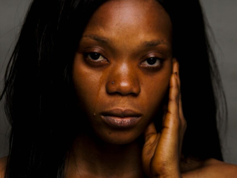 woman with black hair holding her face