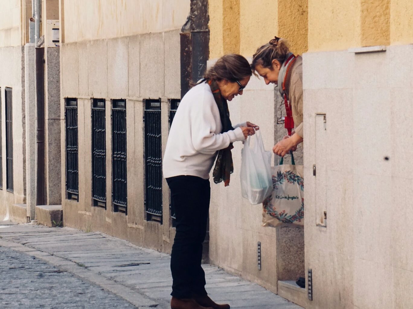 woman in white long sleeve shirt and black pants standing on sidewalk during daytime