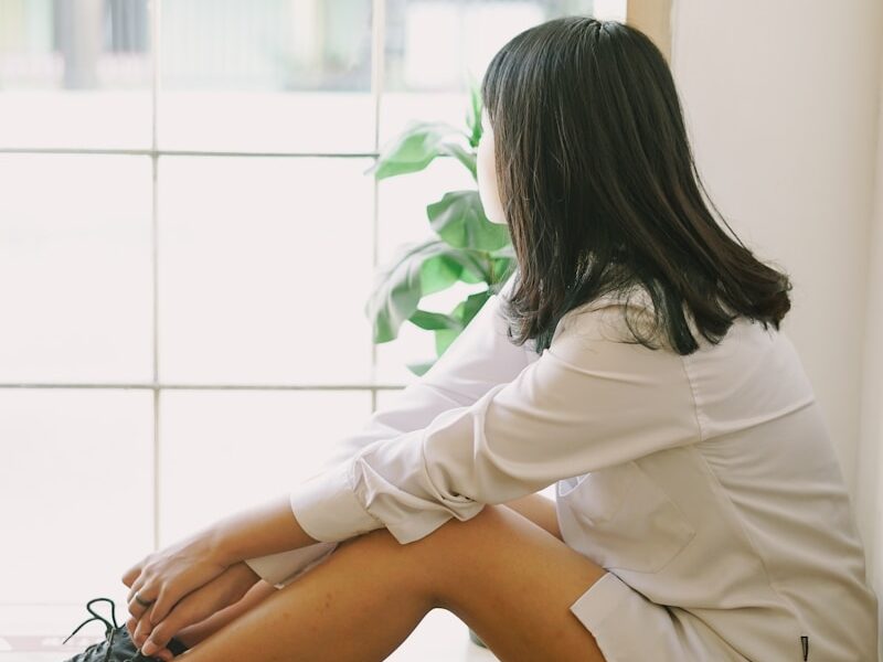 woman in white long sleeve shirt sitting on white floor tiles