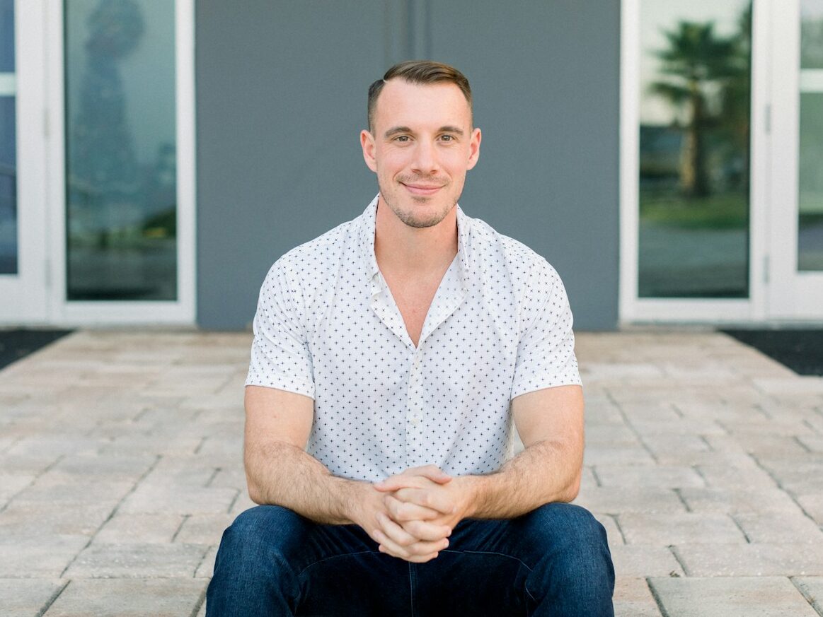 a man sitting on the ground in front of a building