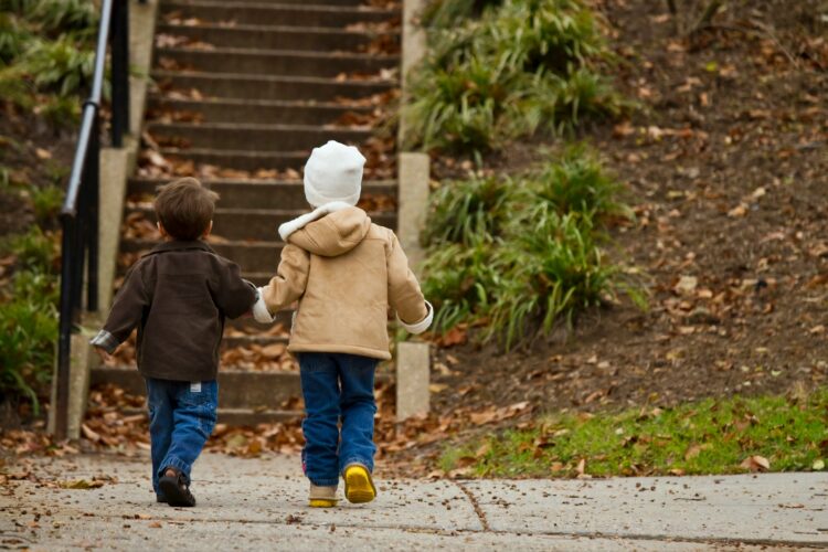 two toddlers walking towards stairs