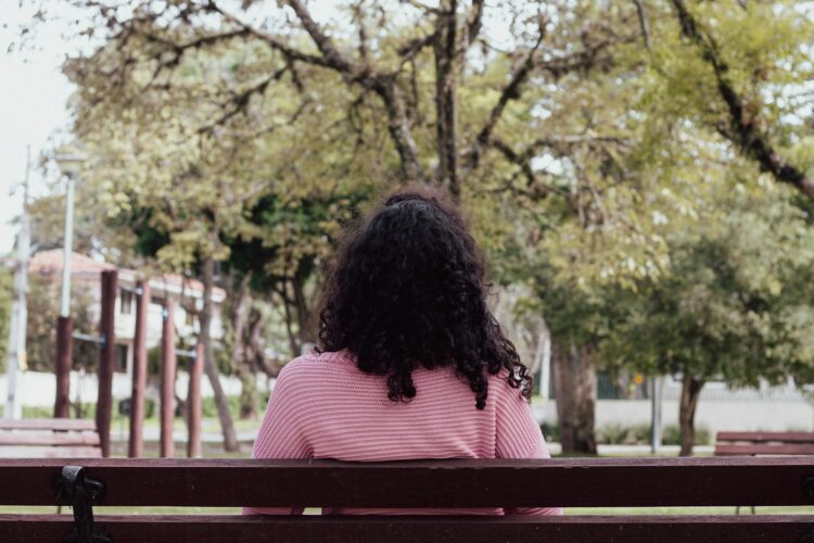 a woman sitting on top of a wooden bench