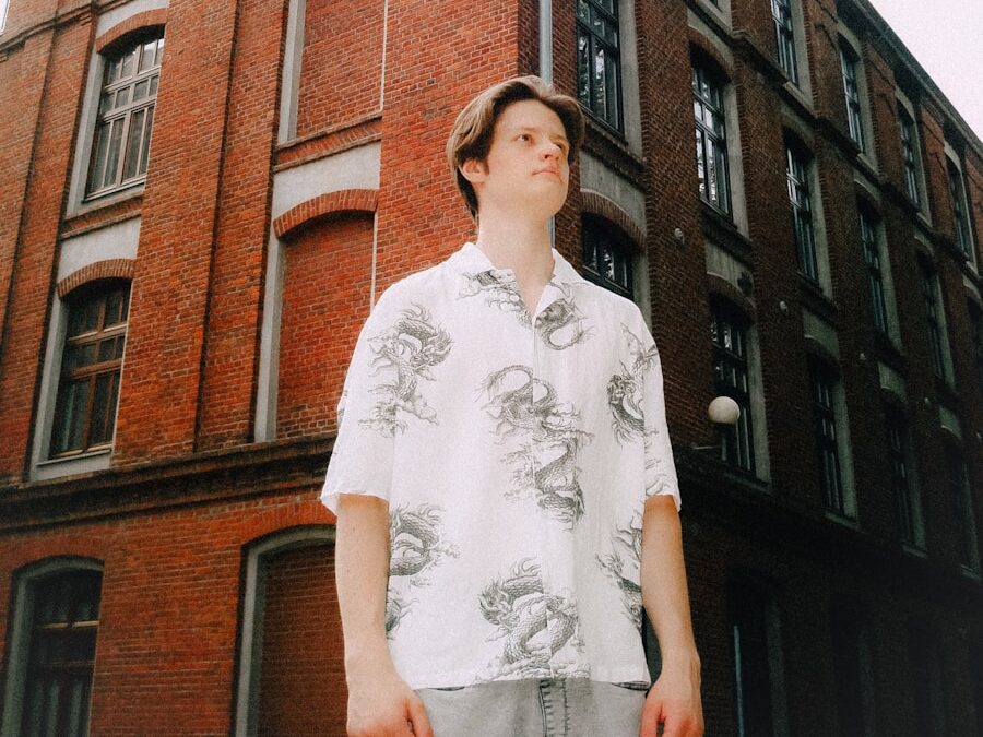 Young man stands before a brick building