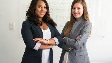 two women in suits standing beside wall