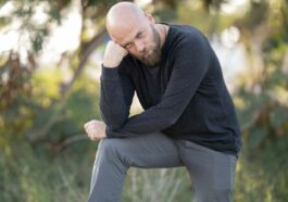 man in black long sleeve shirt and gray pants sitting on green grass during daytime