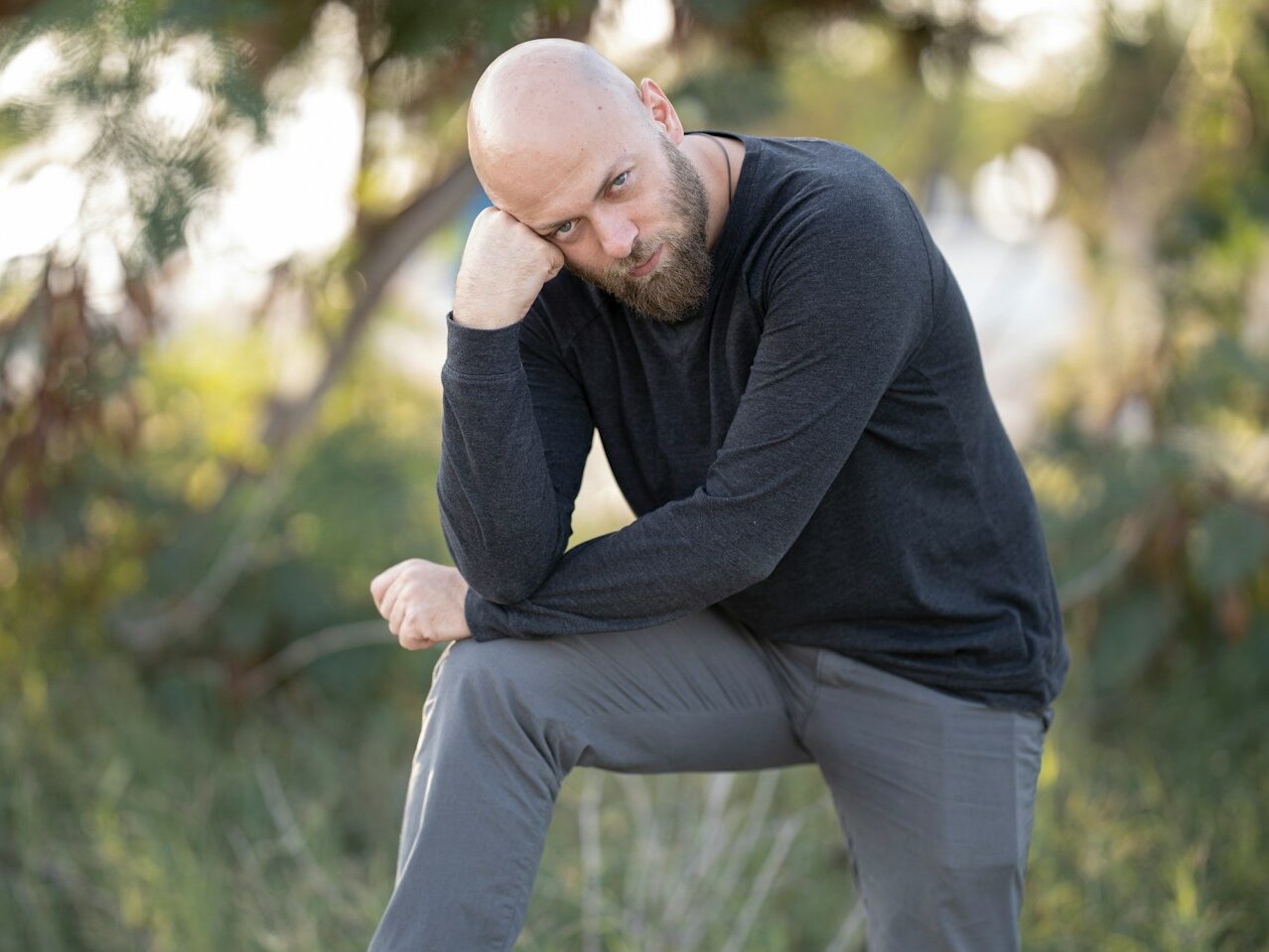 man in black long sleeve shirt and gray pants sitting on green grass during daytime