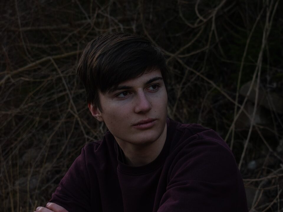 man in purple long sleeve shirt sitting on green grass field