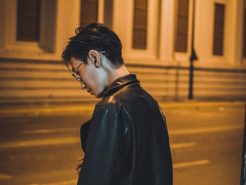 man in black coat standing on the sidewalk