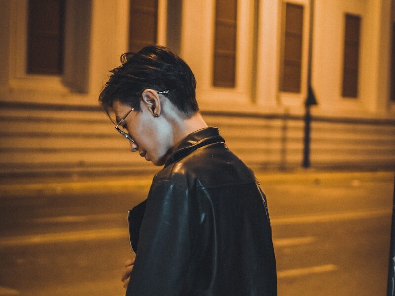 man in black coat standing on the sidewalk