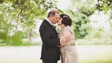 man and woman kissing on green grass field during daytime