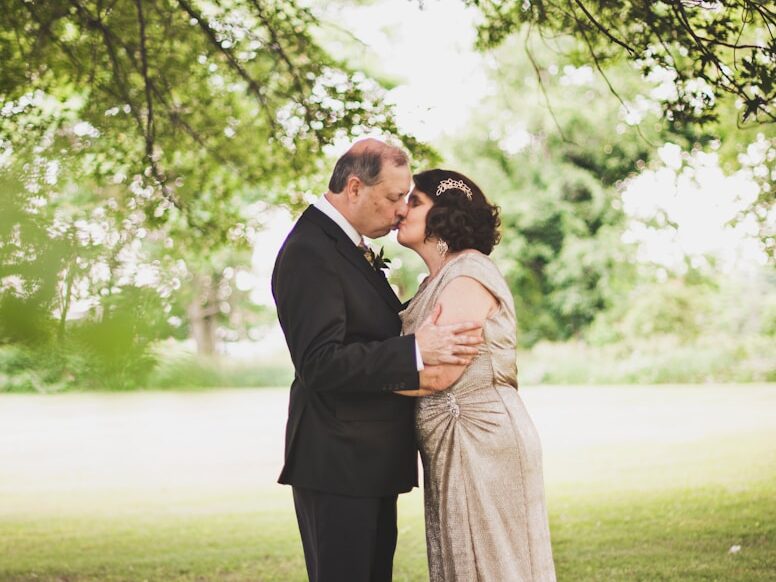 man and woman kissing on green grass field during daytime