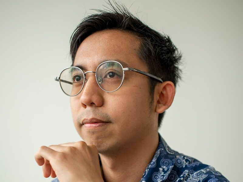 A man with glasses looks off to the side.