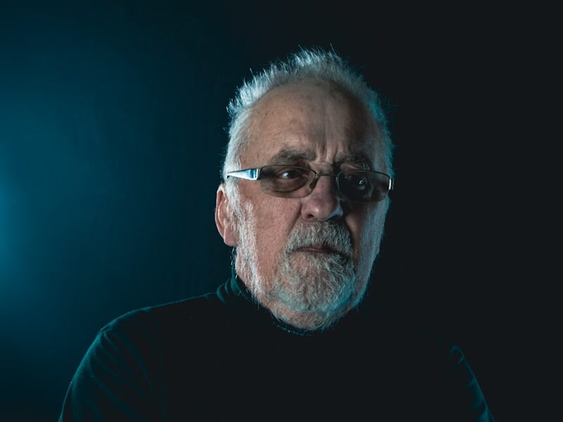 a man with a beard and glasses standing with his arms crossed