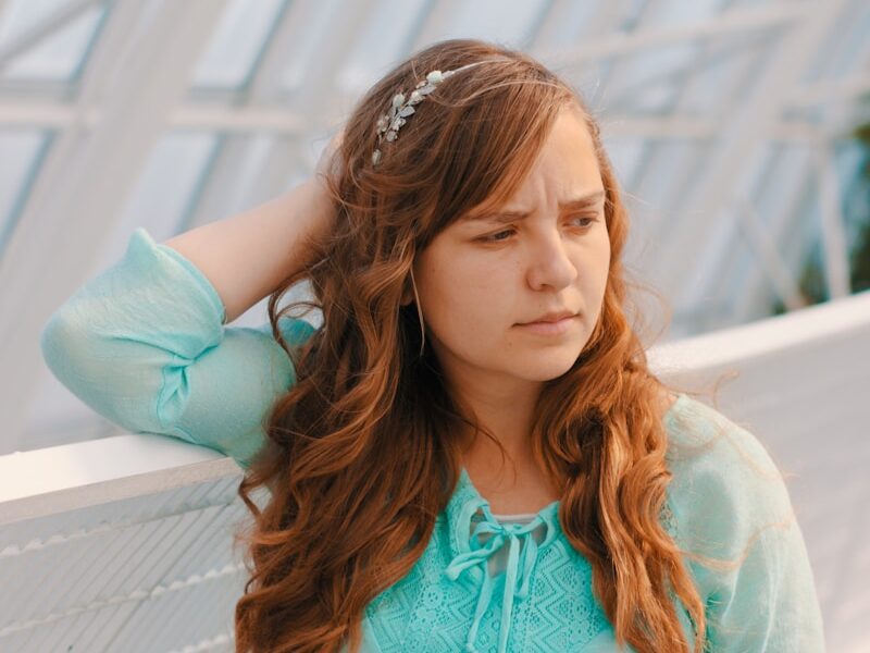 woman holding head near white handrail