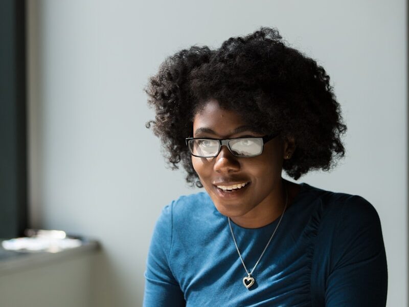 smiling woman wearing blue shirt sitting beside table