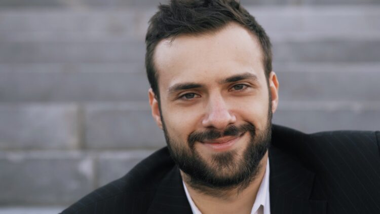 A smiling man with a beard outdoors