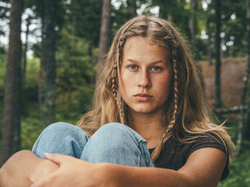 woman in grey shirt and blue denim jeans sitting on ground