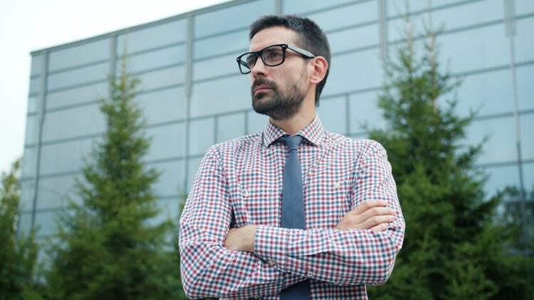 Man in glasses and tie with arms crossed.