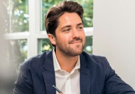 man in black suit jacket holding pen