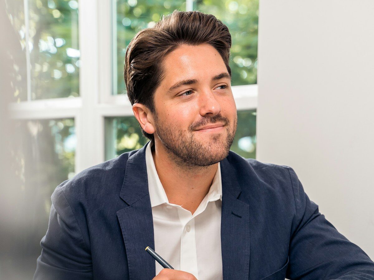 man in black suit jacket holding pen