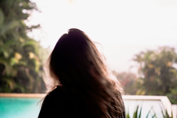 a woman's back with a pool and trees in the background