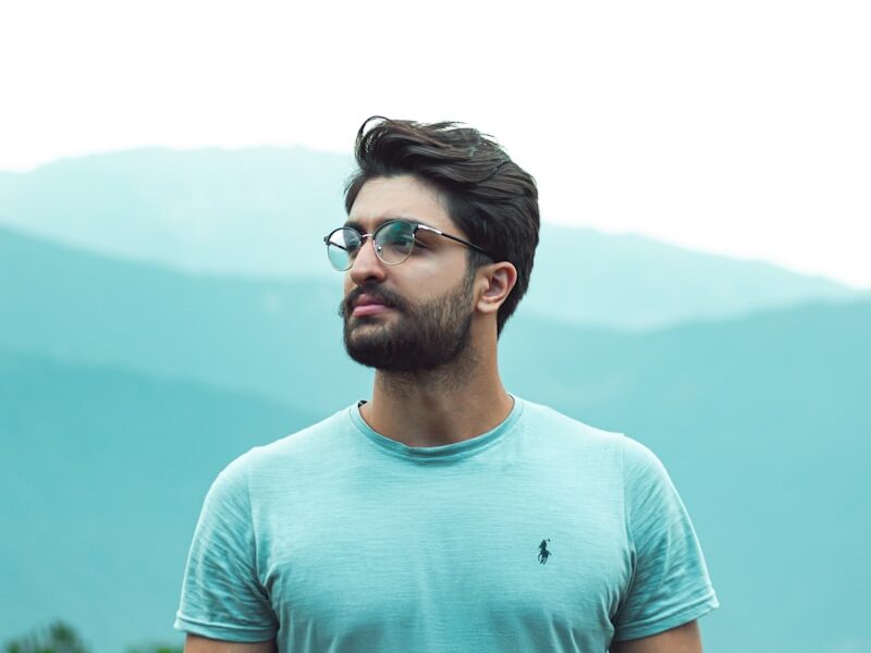 man in teal crew neck shirt wearing black framed eyeglasses
