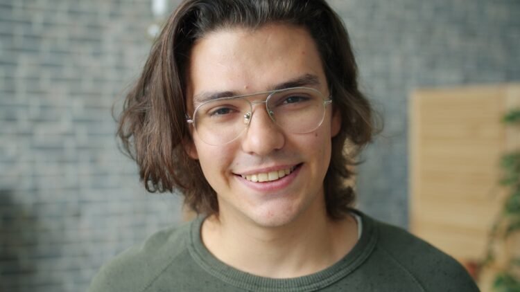 Young man with glasses smiles at the camera