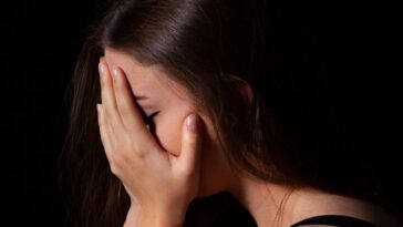 a woman sitting down with her hands on her face
