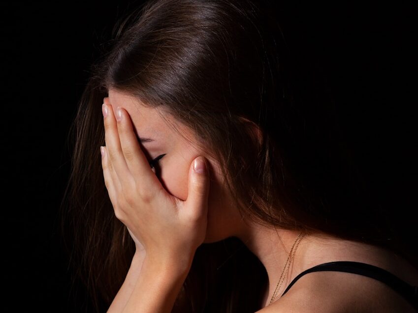 a woman sitting down with her hands on her face