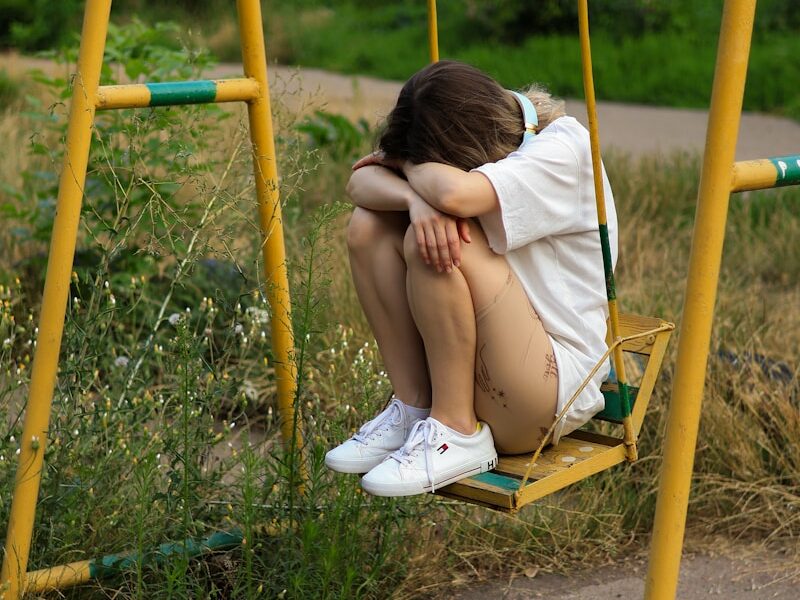 a woman sitting on a swing in a park