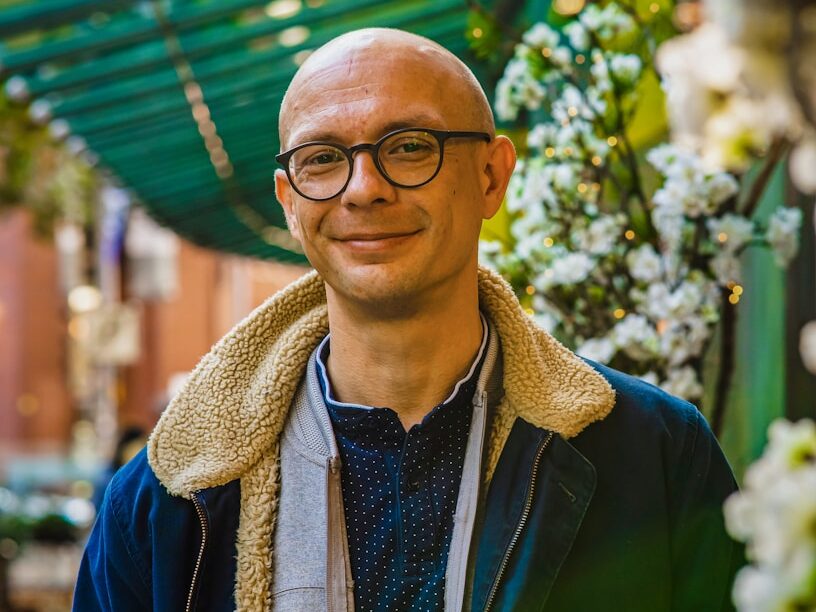 A man standing in front of a bunch of flowers